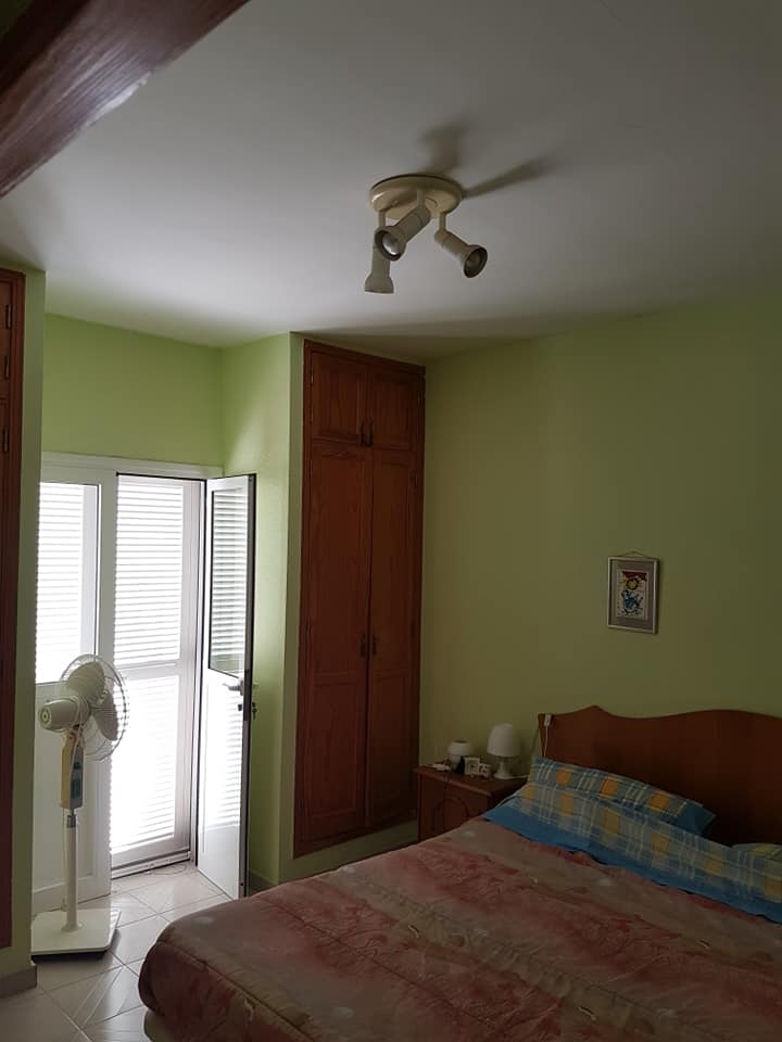 Ein Schlafzimmer mit einem Bett, einem Ventilator, einem Deckenventilator und einer Tür.