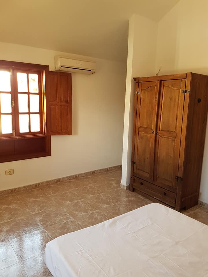 Ein Schlafzimmer mit Bett, Kleiderschrank und Fenster.