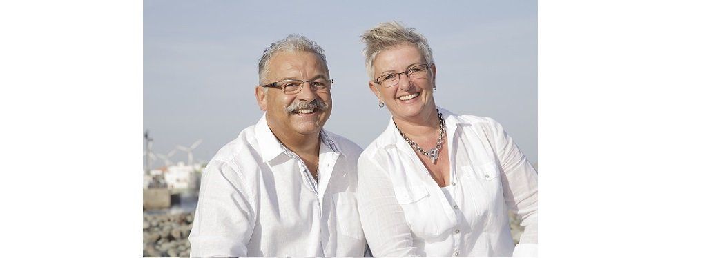 Ein Mann und eine Frau posieren in weißen Hemden für ein Foto.