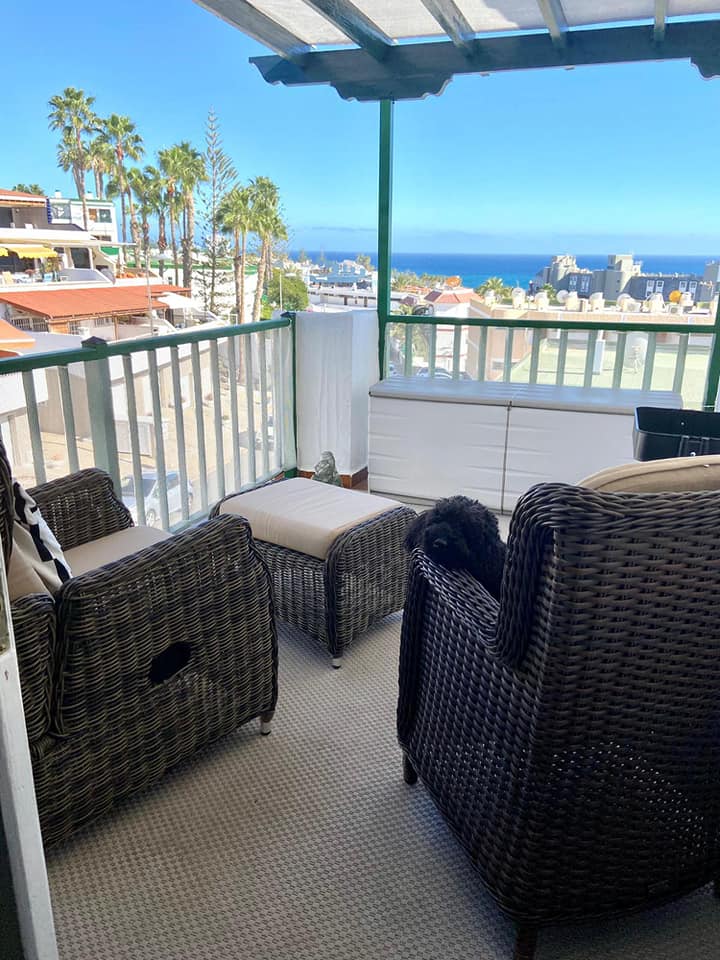 Ein Balkon mit Korbmöbeln und Blick auf das Meer