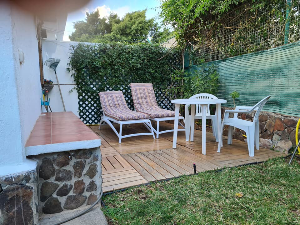 Eine Terrasse mit Tisch und Stühlen im Hinterhof eines Hauses.