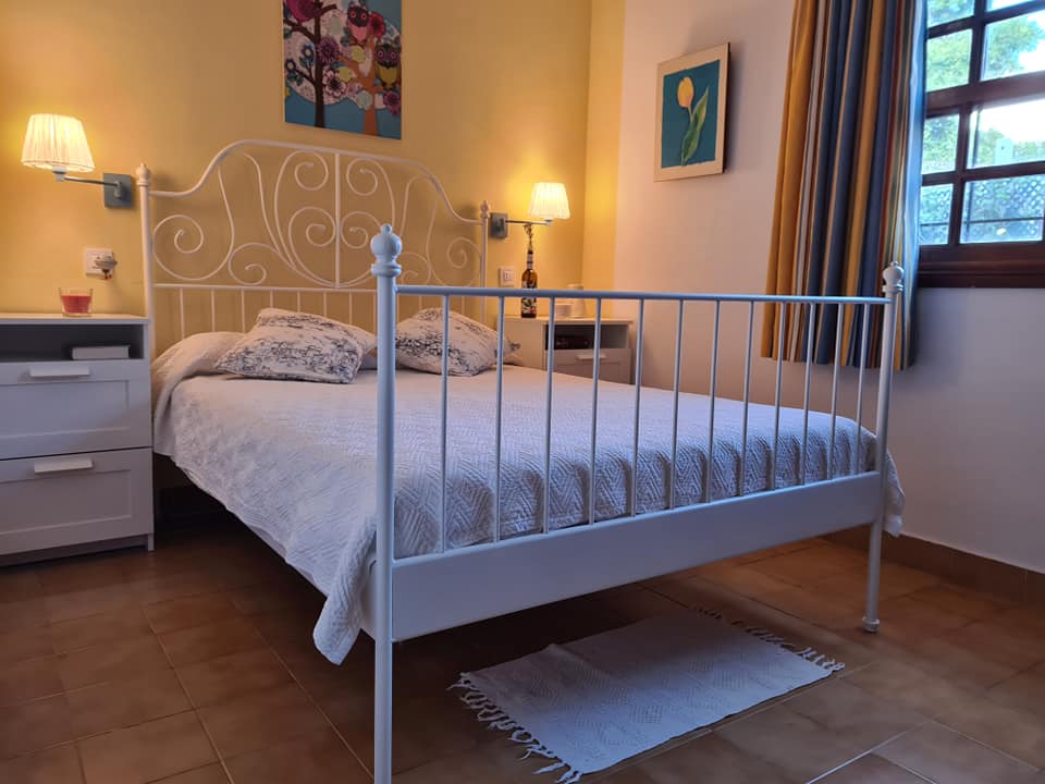Ein Schlafzimmer mit einem Bett, zwei Nachttischen, zwei Lampen und einem Bild an der Wand.