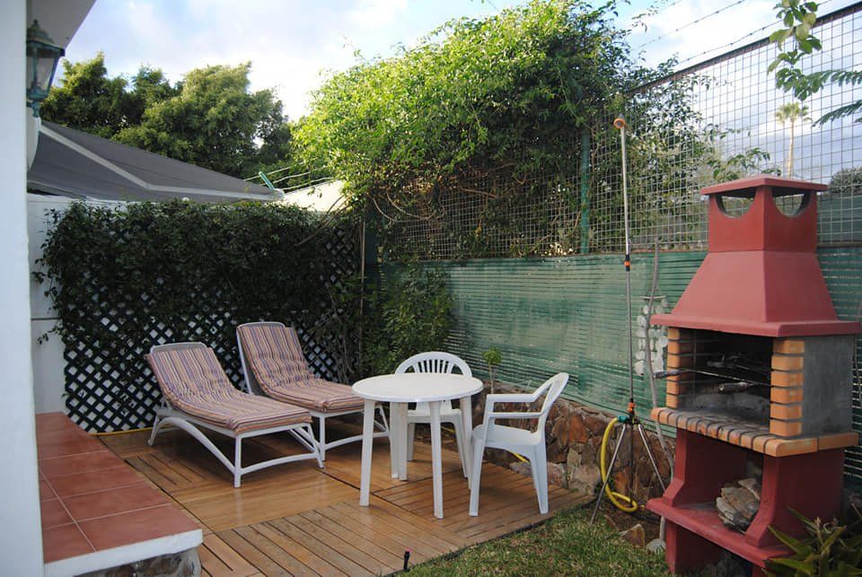 Eine Terrasse mit Tisch und Stühlen und einem Grill