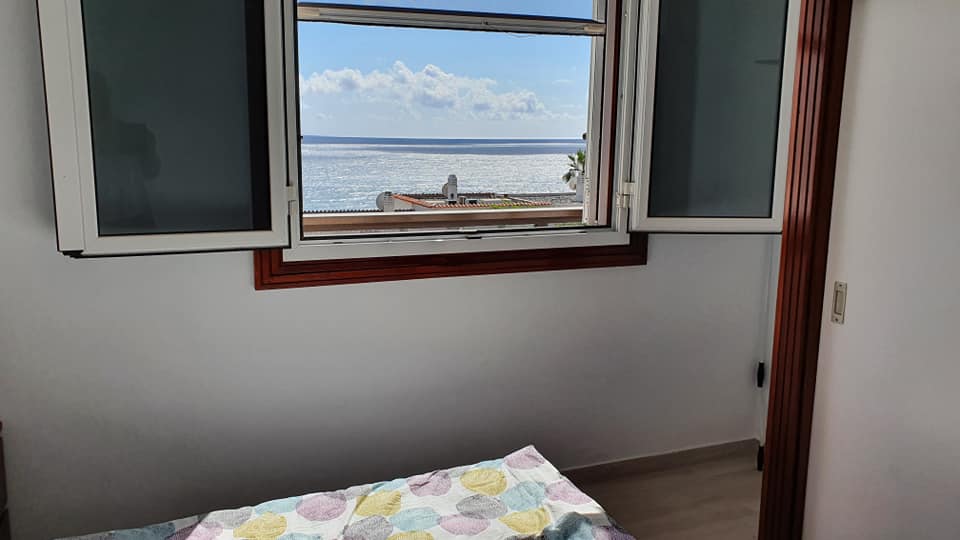 Ein Schlafzimmer mit einem Bett und einem Fenster mit Blick auf das Meer.