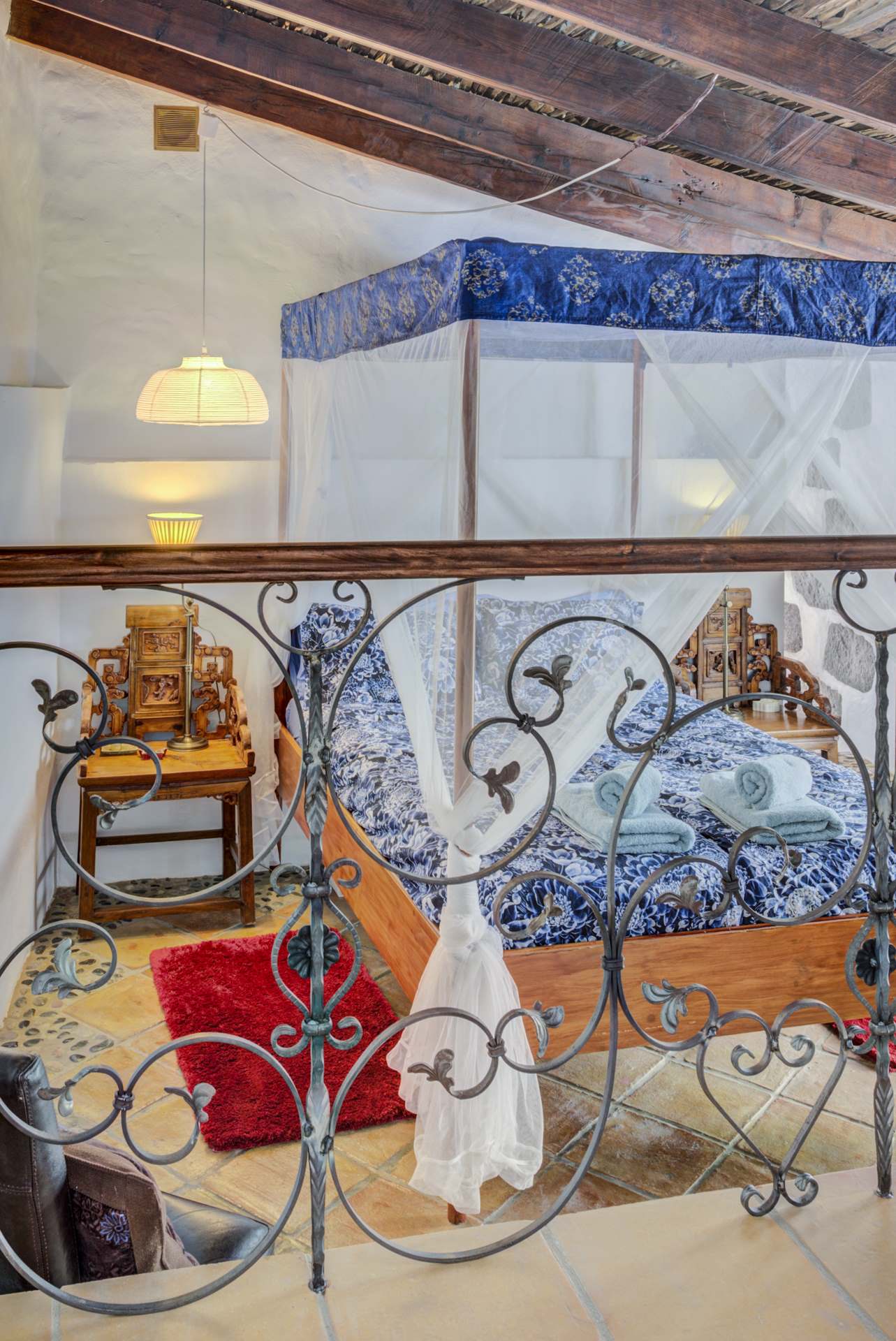 Ein Schlafzimmer mit Himmelbett und schmiedeeisernem Geländer.