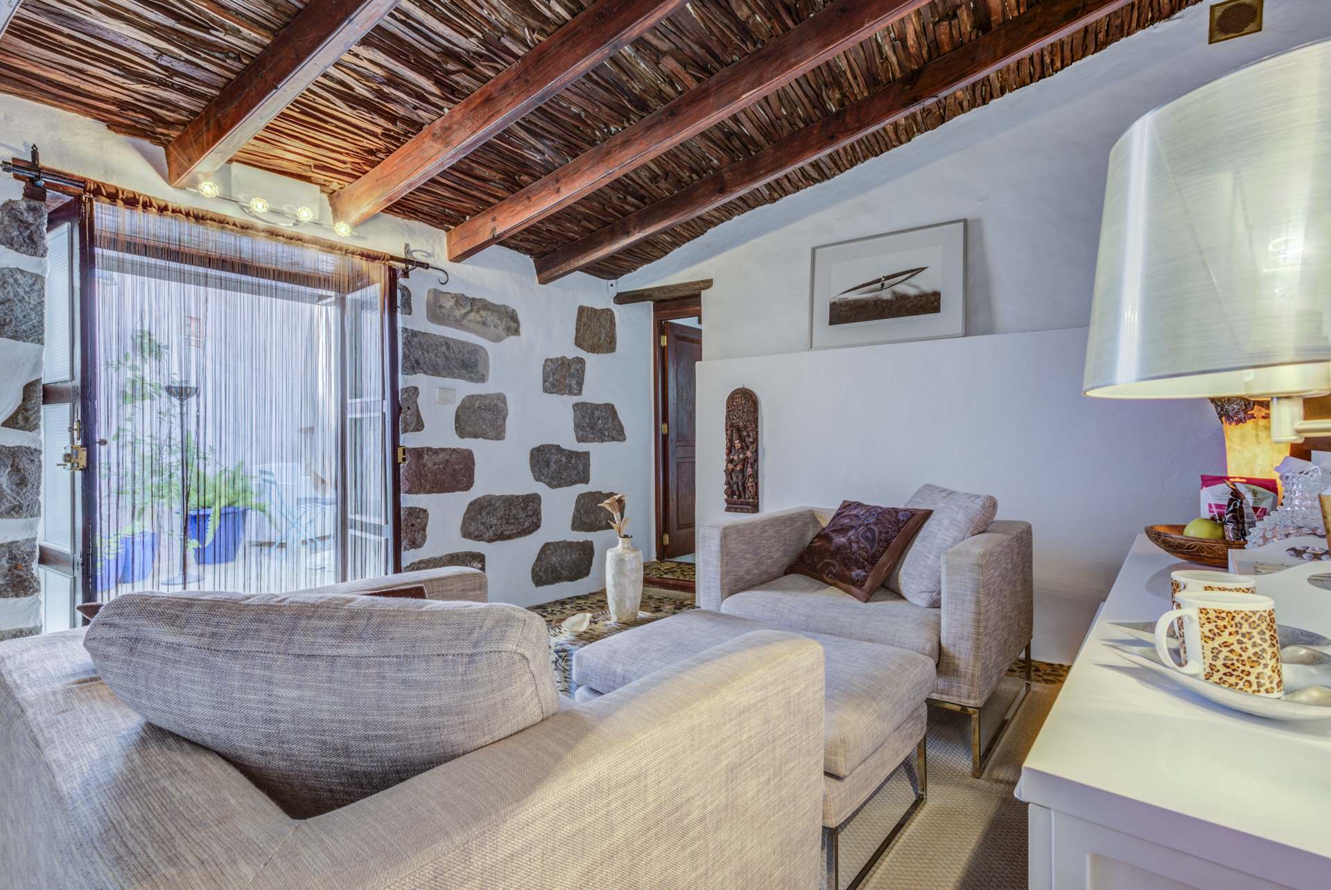 Ein Wohnzimmer mit Couch, Sessel, Tisch und Lampe.