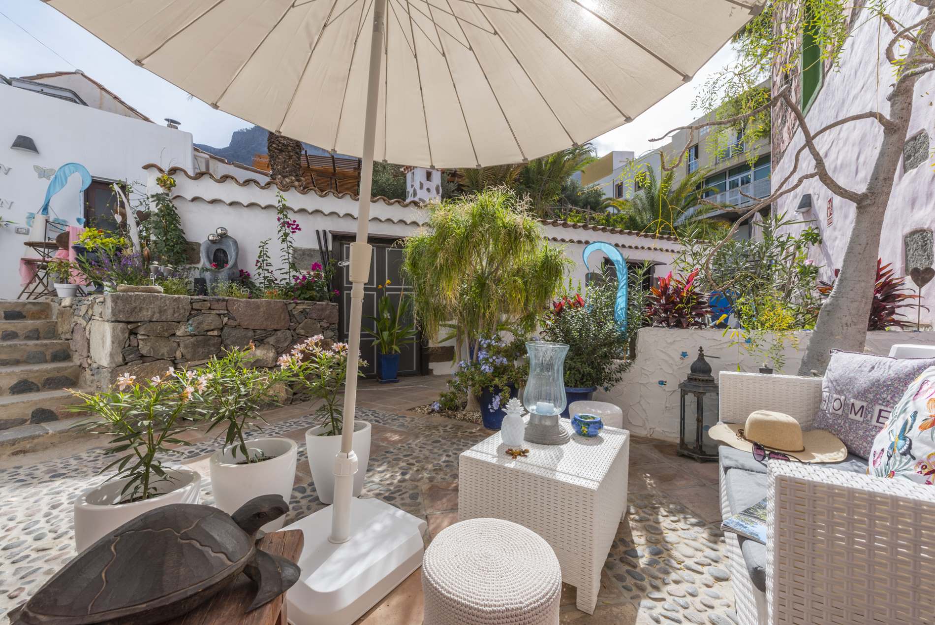 Eine Terrasse mit Sofa, Tisch, Sonnenschirm und einer Schildkrötenstatue.