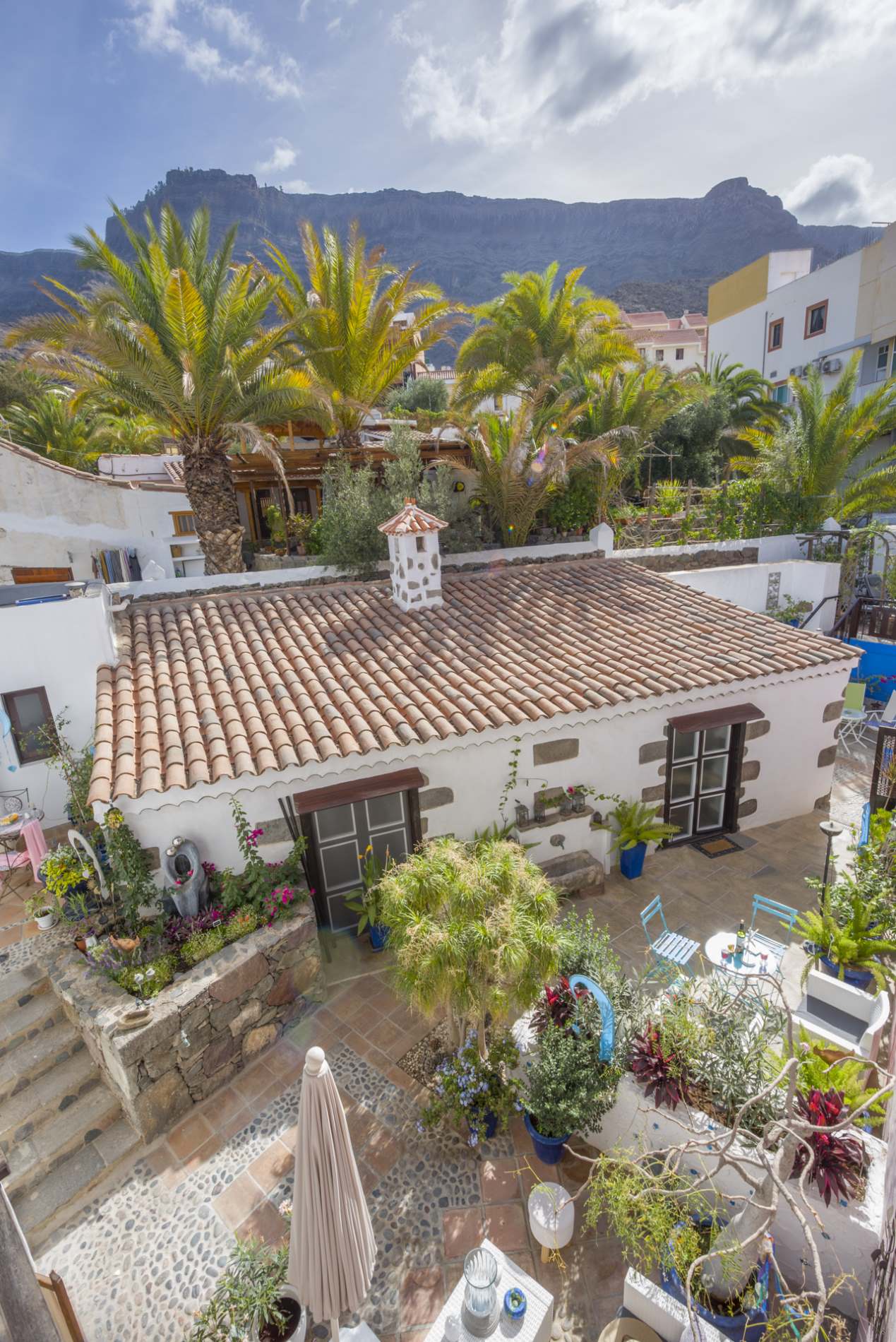 Eine Luftaufnahme eines Hauses mit Ziegeldach und einer Terrasse mit Tischen und Stühlen.