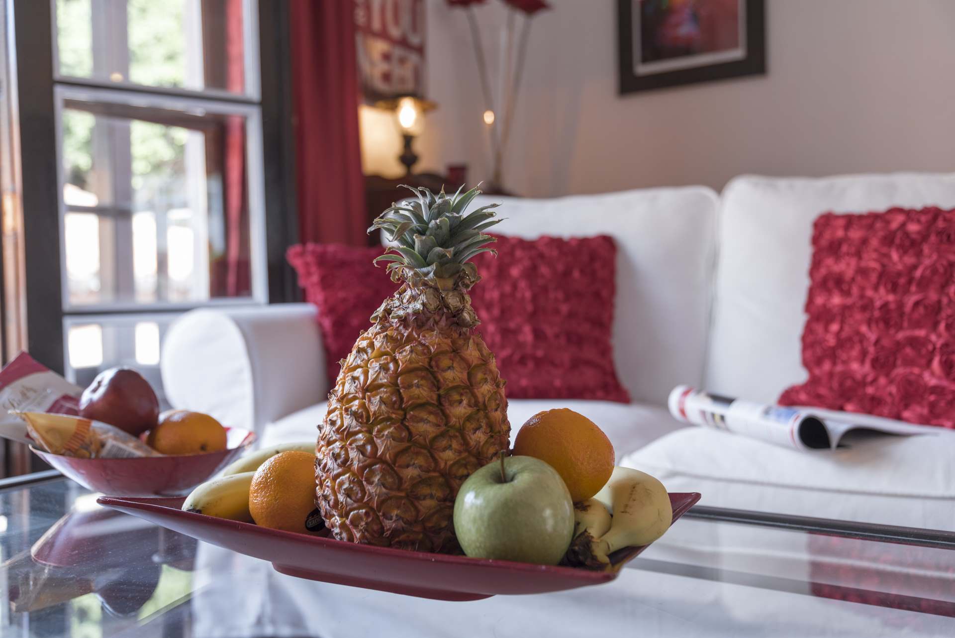 Eine Ananas liegt auf einem Obstteller auf einem Tisch in einem Wohnzimmer.