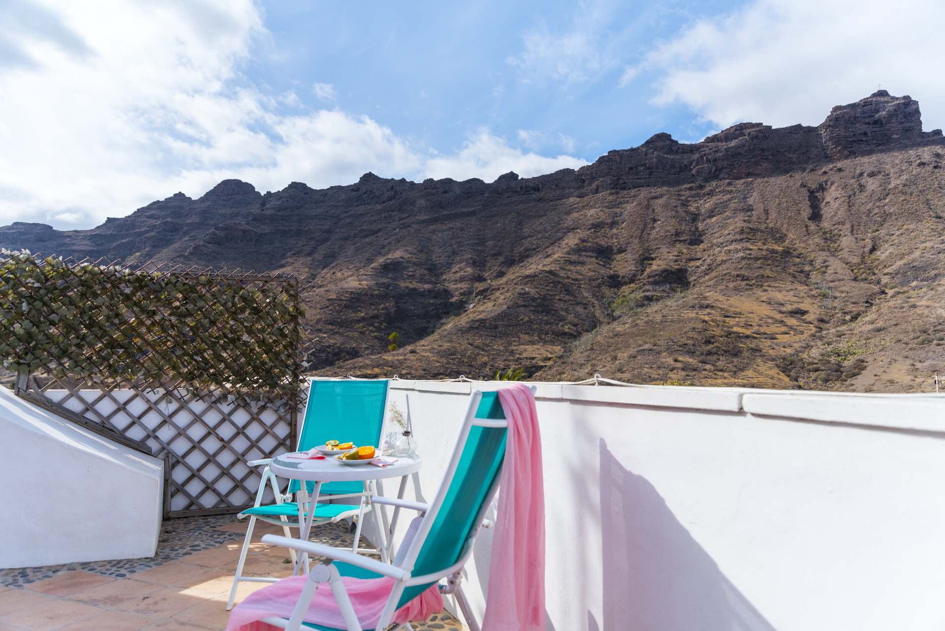 Ein Balkon mit Stühlen und einem Tisch mit Bergen im Hintergrund.