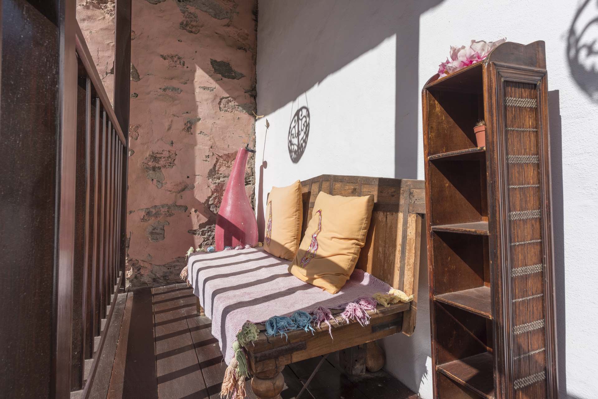 Ein Balkon mit einer Holzbank und einem Bücherregal.