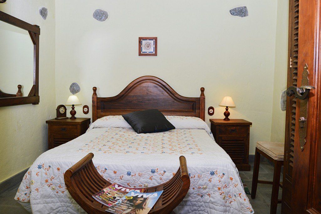 Ein Schlafzimmer mit einem Bett, Nachttischen, einem Spiegel und einer Bank.