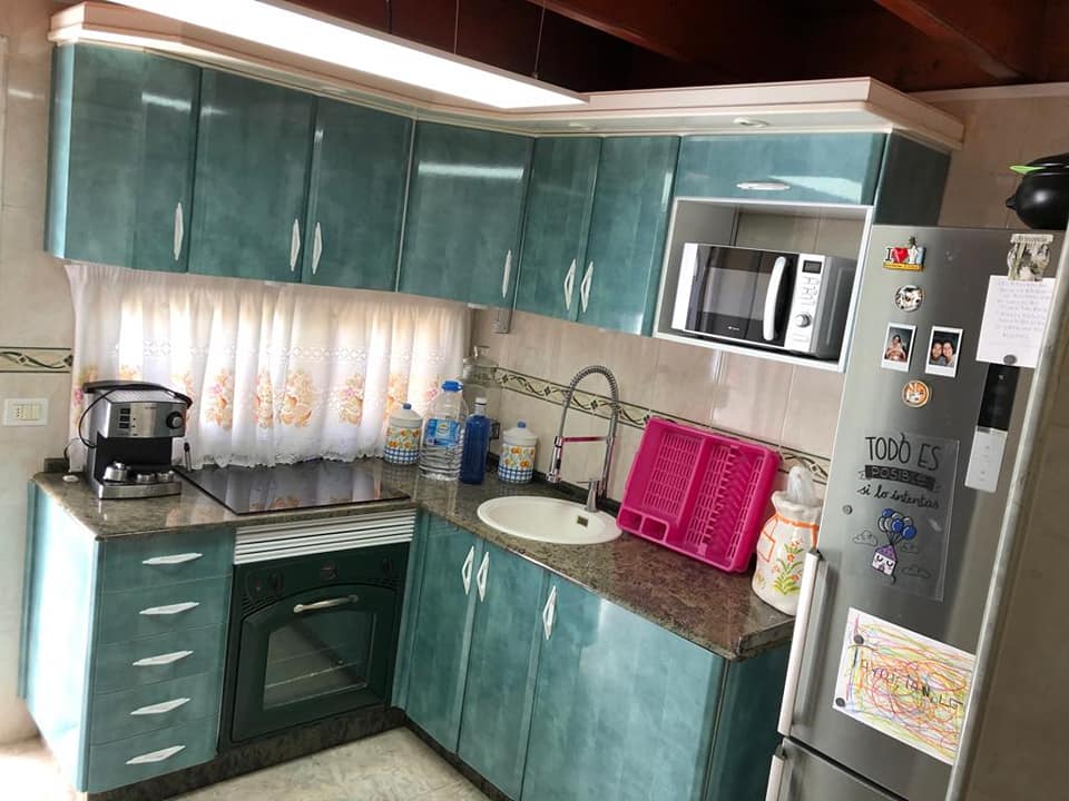 Eine Küche mit blauen Schränken und einem Edelstahlkühlschrank
