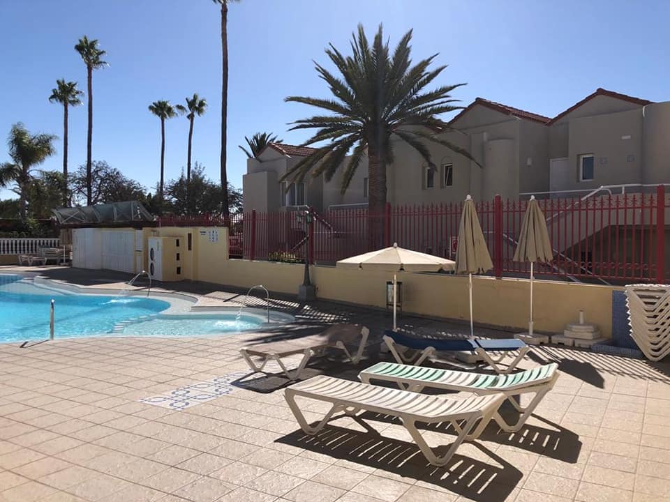 Ein Swimmingpool mit Liegen und Sonnenschirmen vor einem Gebäude.