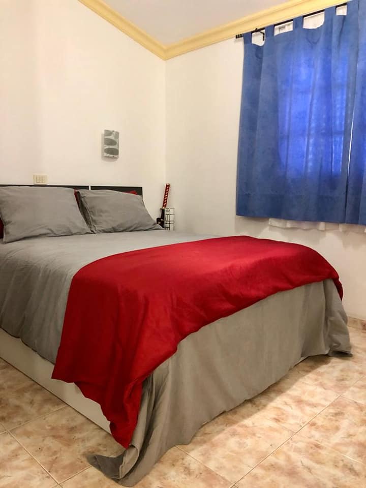 Ein Schlafzimmer mit einem Bett und einem Fenster mit blauen Vorhängen