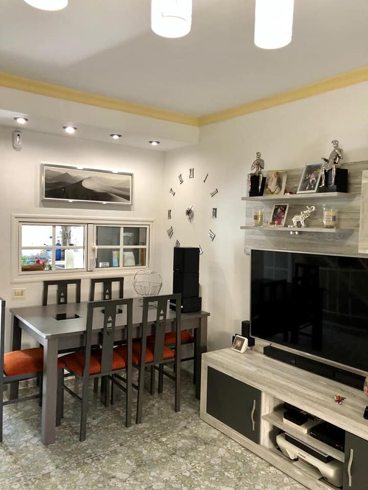 Ein Wohnzimmer mit Tisch und Stühlen und einem Fernseher.