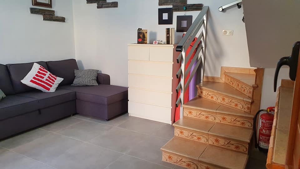 Ein Wohnzimmer mit Couch, Treppe und Feuerlöscher.
