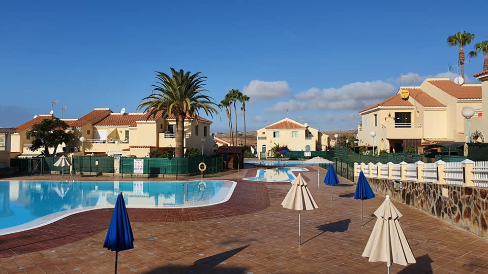 Ein Swimmingpool mit Sonnenschirmen vor einer Häuserzeile.