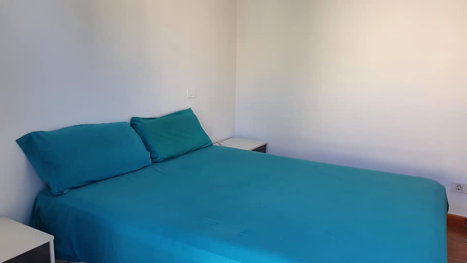 Ein Schlafzimmer mit einem Bett, zwei Nachttischen und einer blauen Decke.