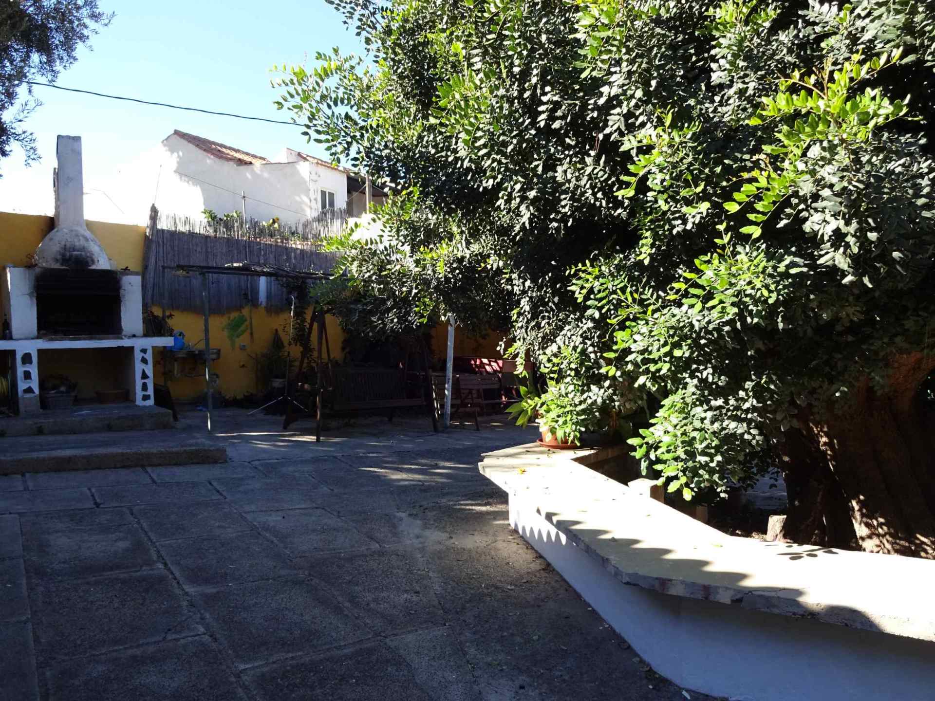 Eine Terrasse mit Grill und Bäumen vor einem Haus