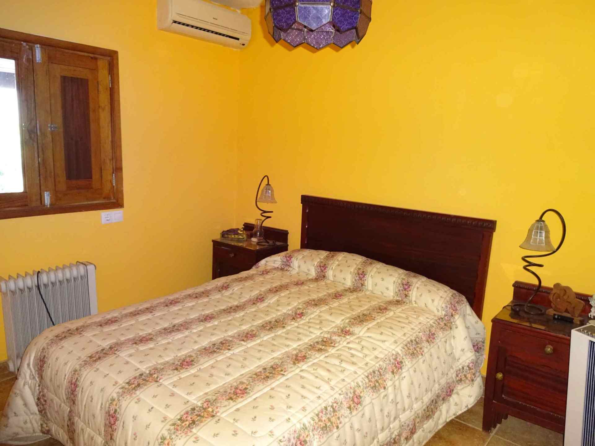 Ein Schlafzimmer mit gelben Wänden und einem Bett mit geblümter Bettdecke