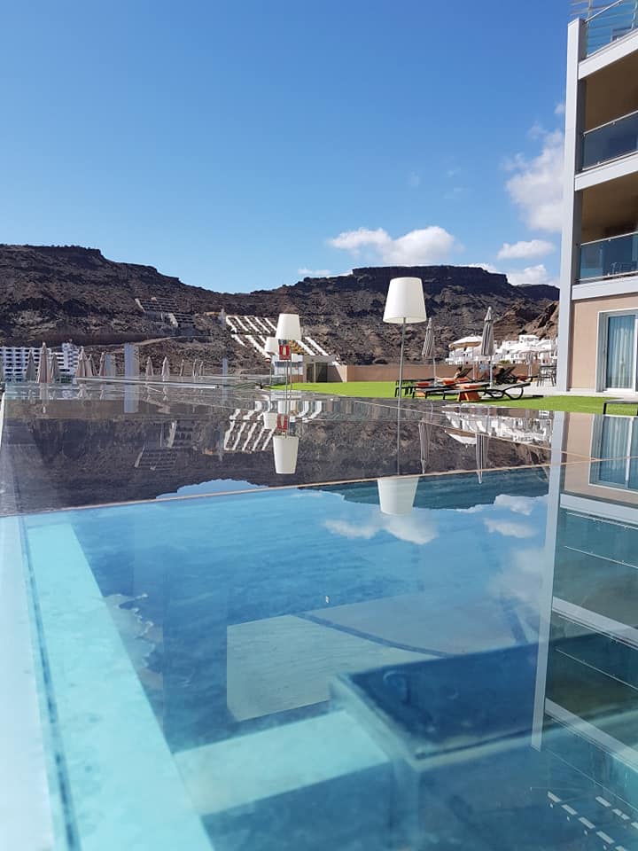 Ein Swimmingpool mit Blick auf Berge und ein Gebäude im Hintergrund.