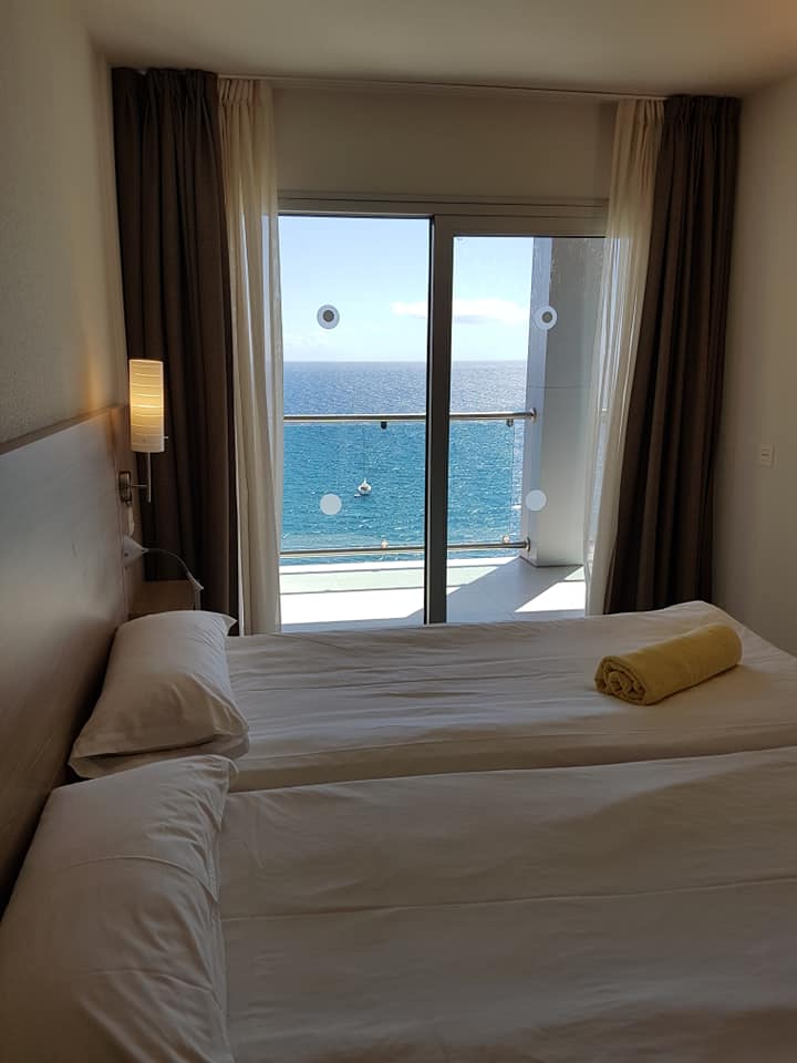 Ein Hotelzimmer mit zwei Betten und einem Balkon mit Blick auf den Ozean.