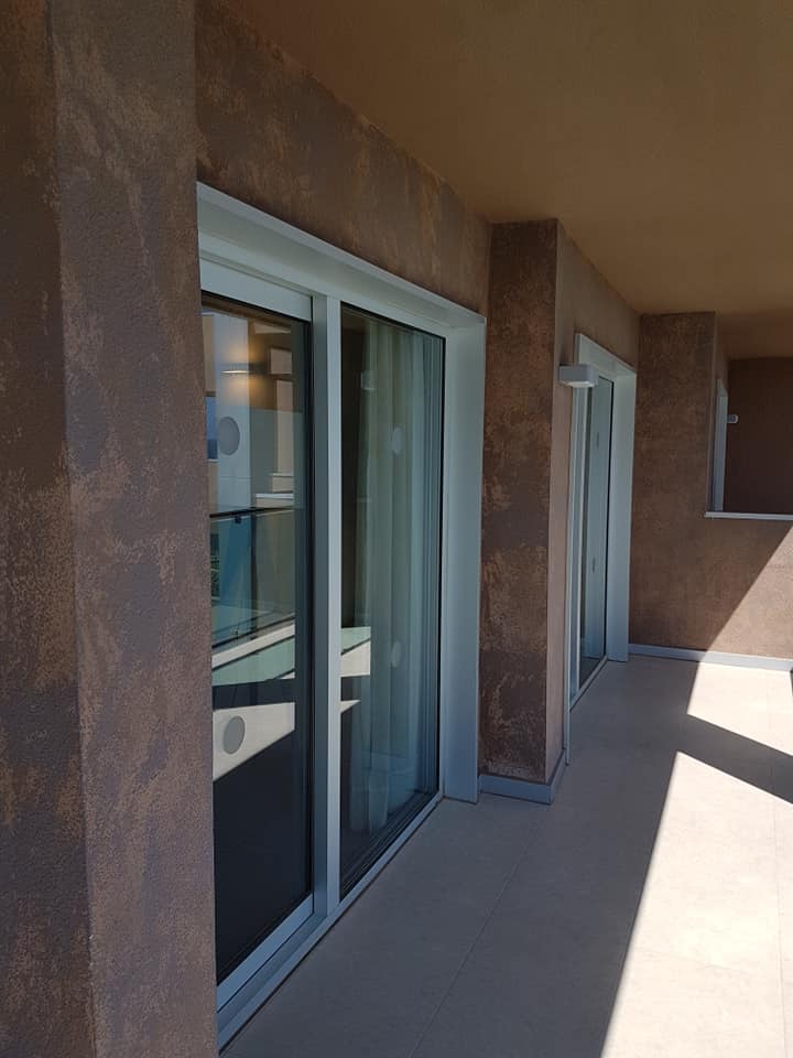 Ein Balkon mit Glasschiebetüren und einer braunen Wand.