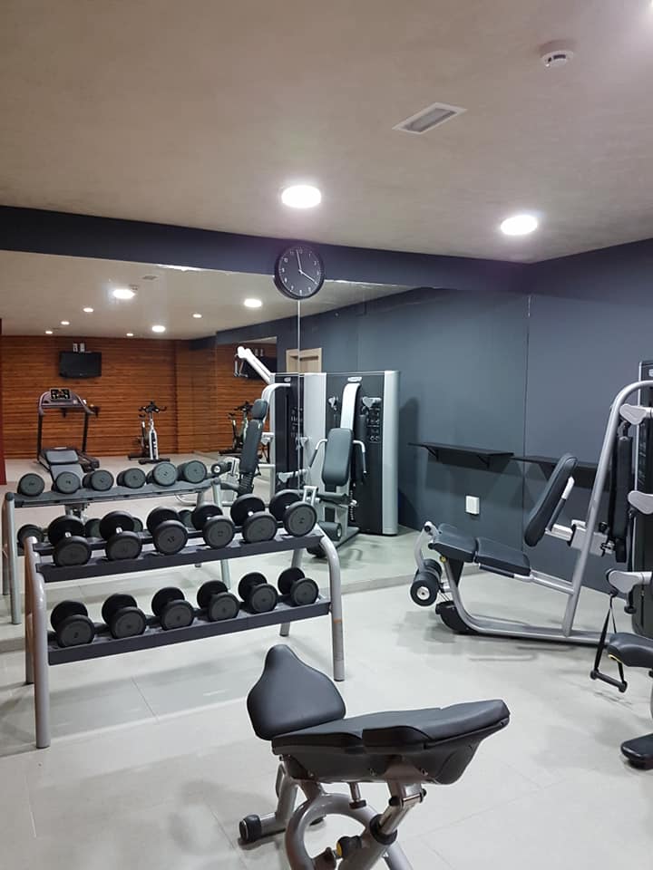 Ein Fitnessstudio mit vielen Geräten und einer Uhr an der Wand.