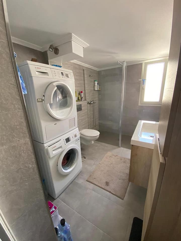 Ein Badezimmer mit einer übereinander gestapelten Waschmaschine und einem Trockner.