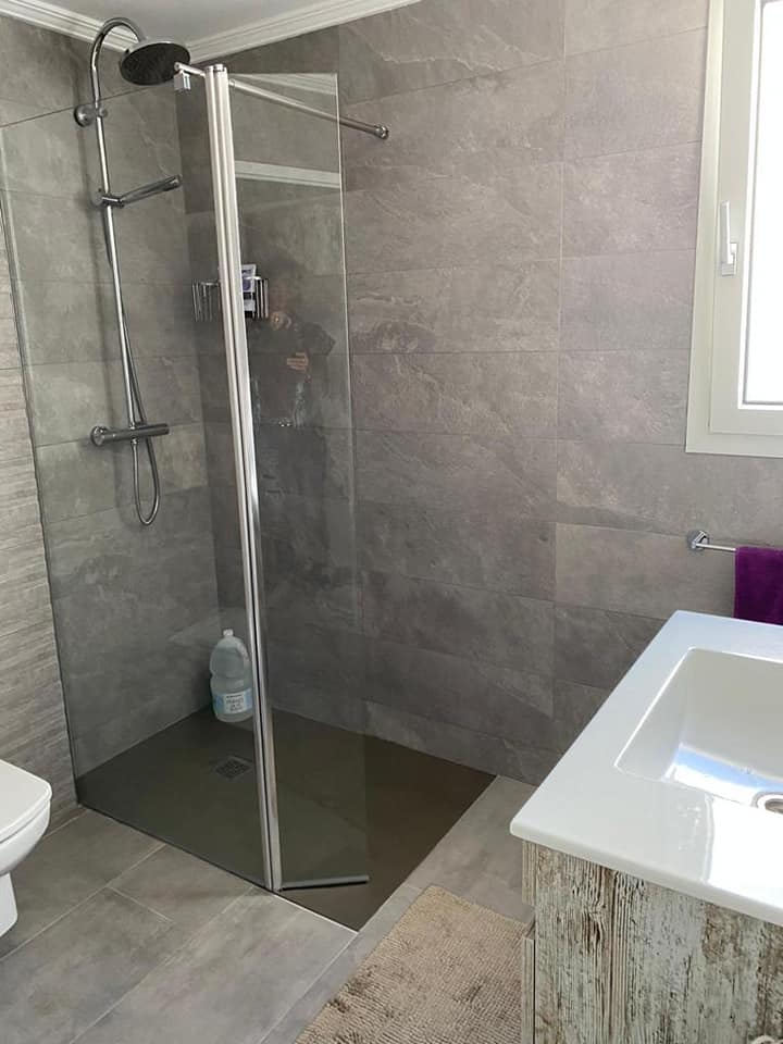 Ein Badezimmer mit ebenerdiger Dusche und Waschbecken.
