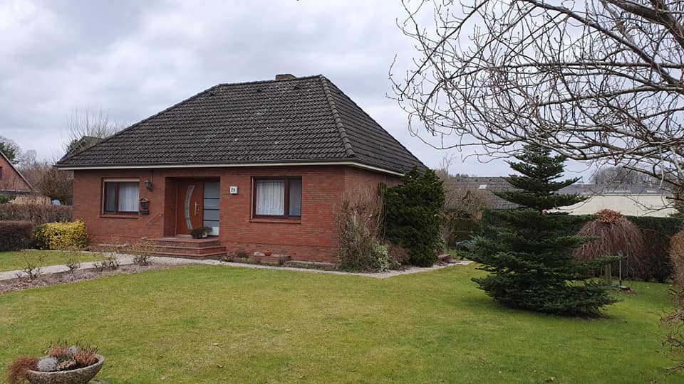Ein Backsteinhaus mit schwarzem Dach und einer großen Wiese davor