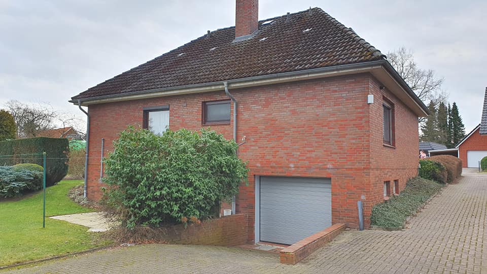 Ein Backsteinhaus mit Garage und Schornstein auf dem Dach.
