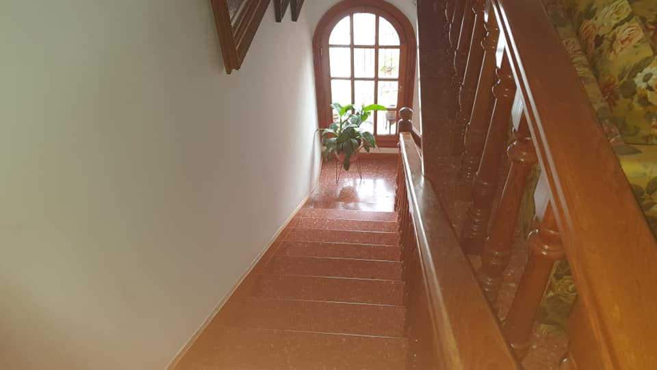 Ein langer Flur mit einer Treppe, die zu einem Fenster hinaufführt.