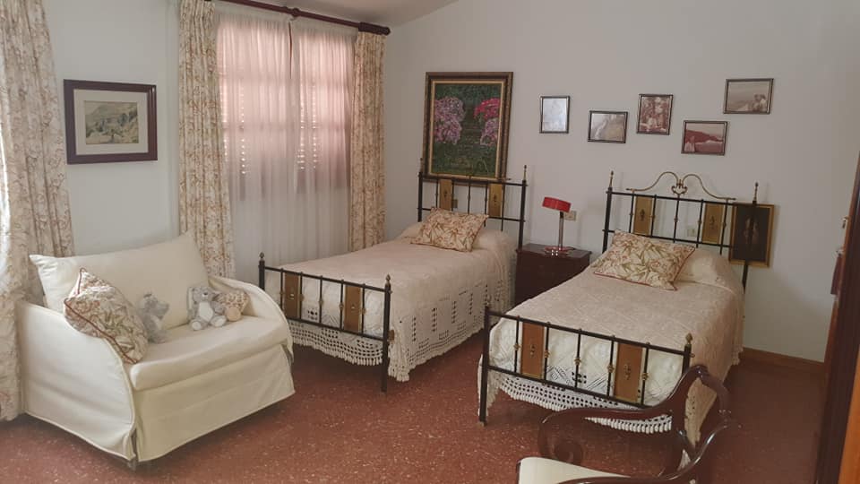 Ein Schlafzimmer mit zwei Betten, einer Couch und einem Sessel.