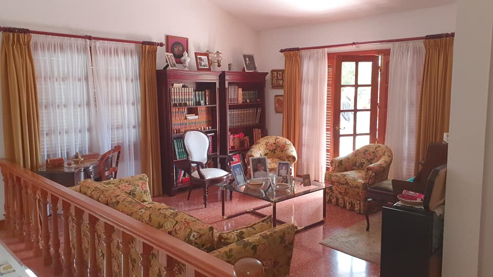 Ein Wohnzimmer mit einer Couch, Stühlen, einem Couchtisch und einem Bücherregal.