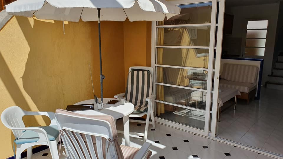 Eine Terrasse mit Tisch und Stühlen unter einem Sonnenschirm.