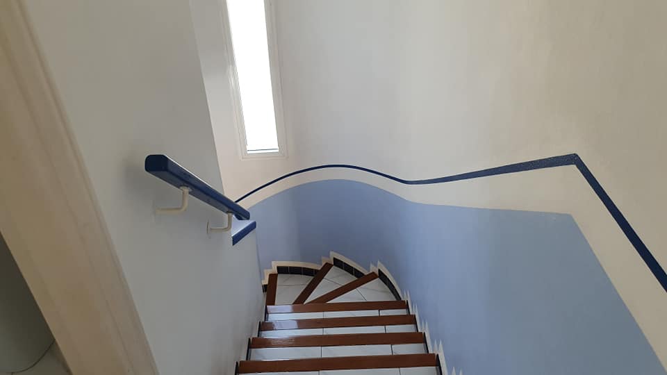 Die Treppe ist blau und weiß gestrichen und hat ein blaues Geländer.