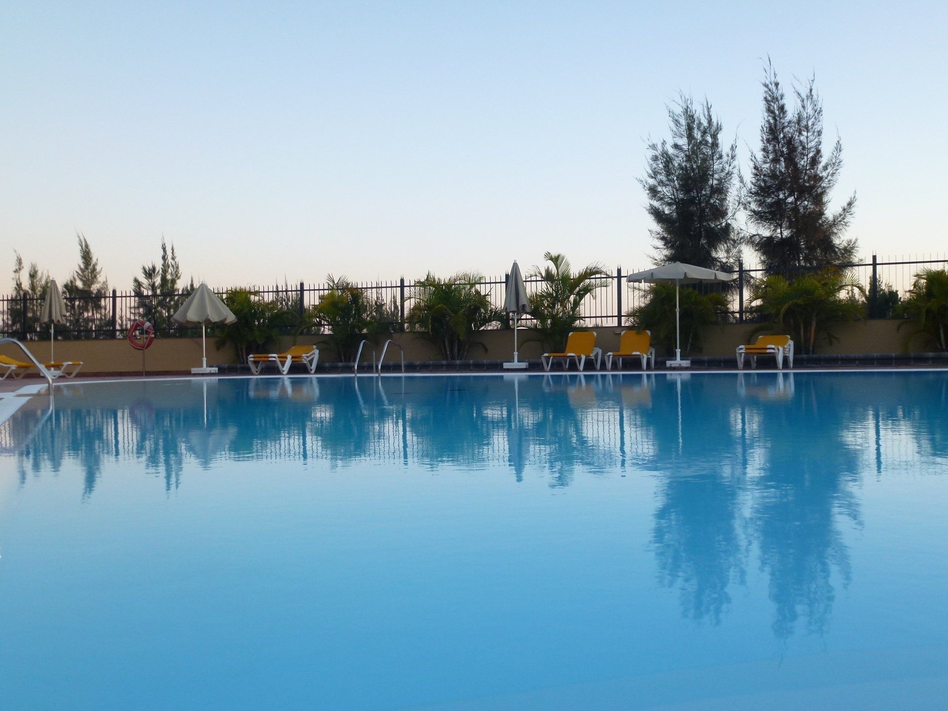 Ein großer Swimmingpool mit Stühlen und Sonnenschirmen drumherum