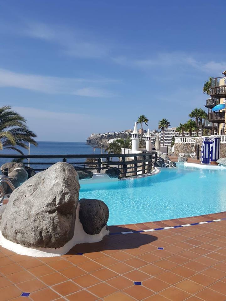 Ein großer Felsen liegt vor einem Swimmingpool mit Blick auf den Ozean