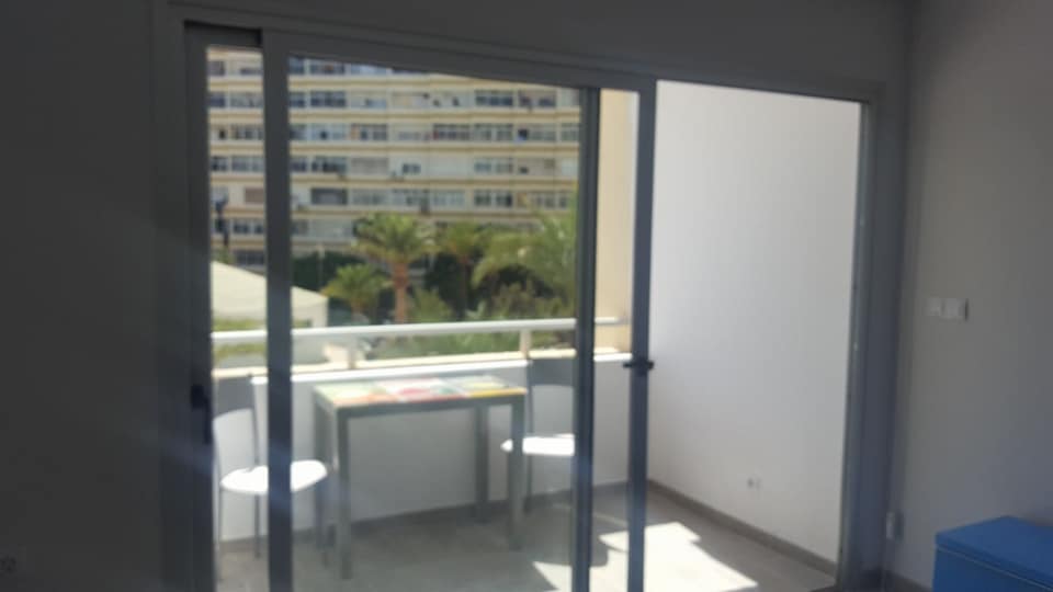 Eine Glasschiebetür öffnet sich zu einem Balkon mit Tisch und Stühlen