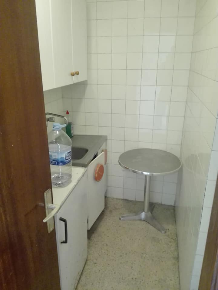 Eine kleine Küche mit einem Tisch und einer Flasche Wasser auf der Theke.