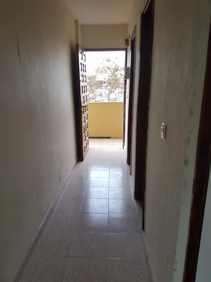 Ein langer Flur mit einer Tür, die zu einem Balkon führt.