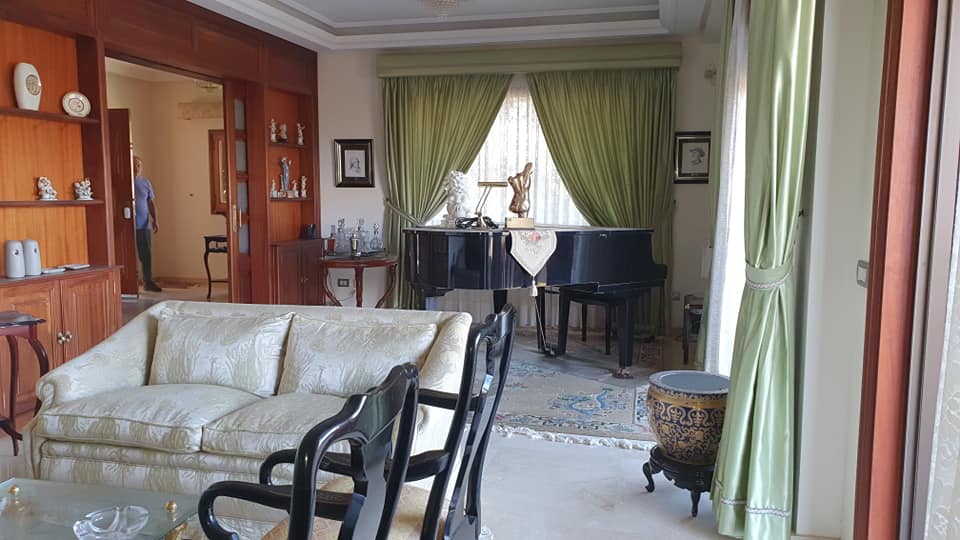 Ein Wohnzimmer mit einer Couch, Stühlen und einem Klavier.
