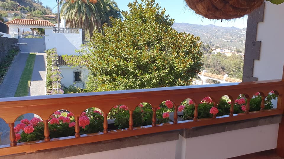 Ein Balkon mit einem Holzgeländer und Blumen darauf