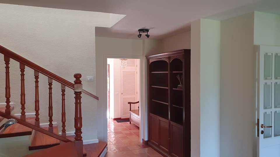 Ein Flur mit Treppe und einem Bücherregal in einem Haus.