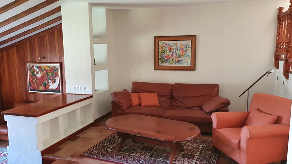 Ein Wohnzimmer mit Sofa, Sessel, Couchtisch und einem Gemälde an der Wand.