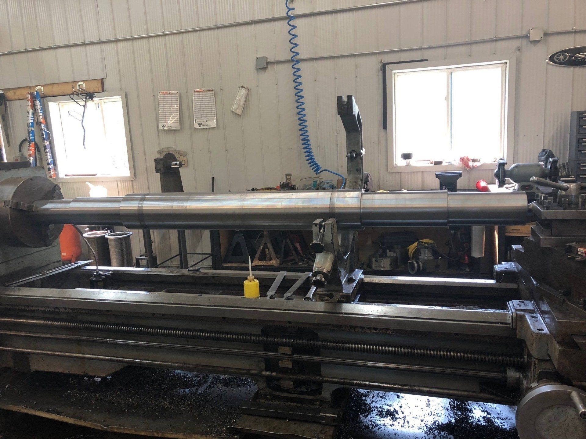 A large lathe is sitting in a room next to a window.