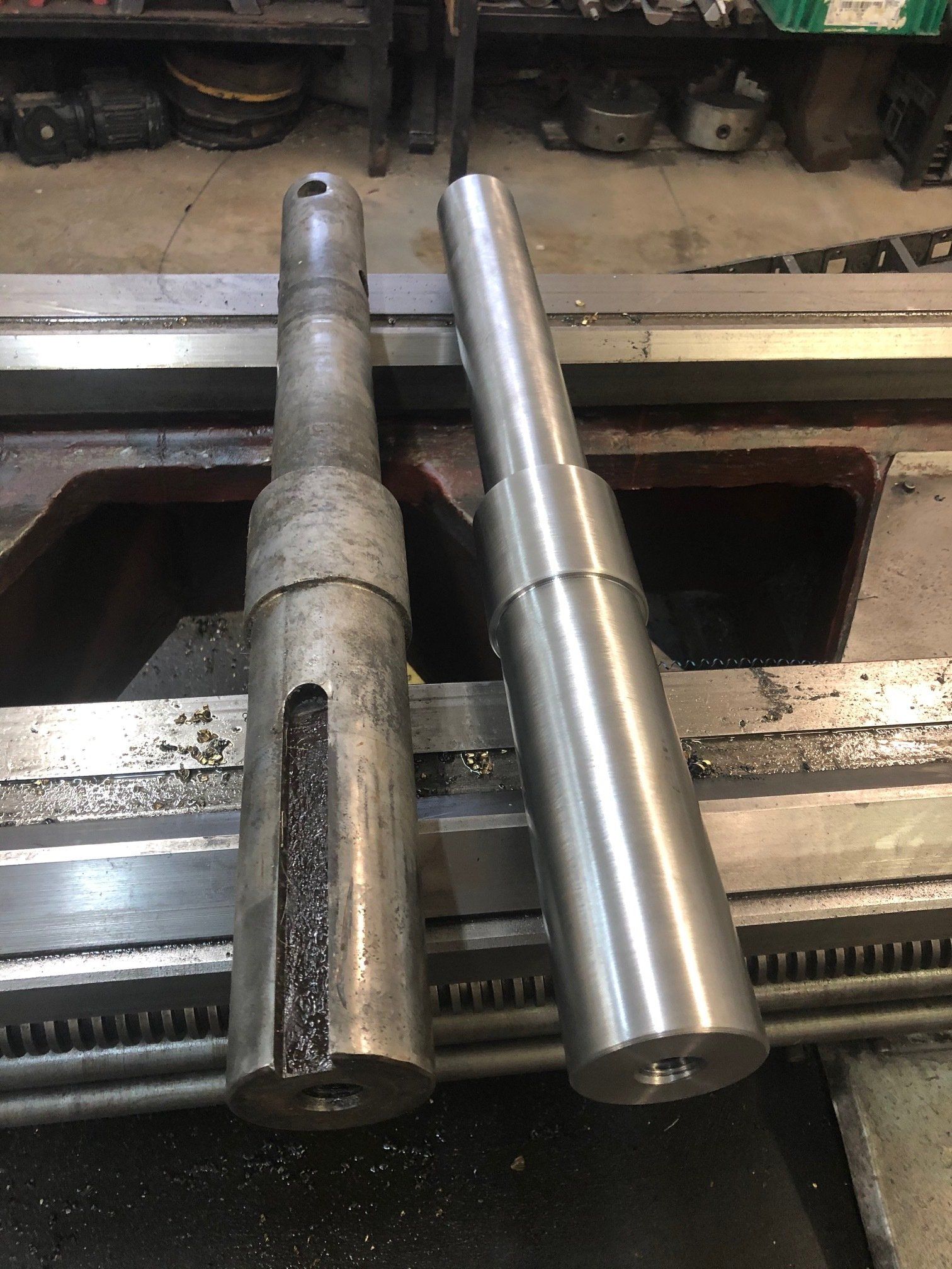 Two metal shafts are sitting on top of a lathe.