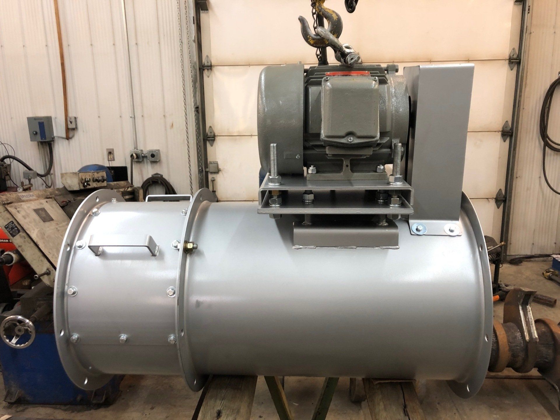 A large gray machine is sitting in front of a garage door.